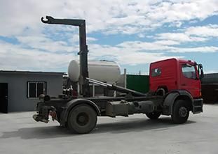 Un camión volquete rojo está estacionado en un estacionamiento al lado de un edificio.
