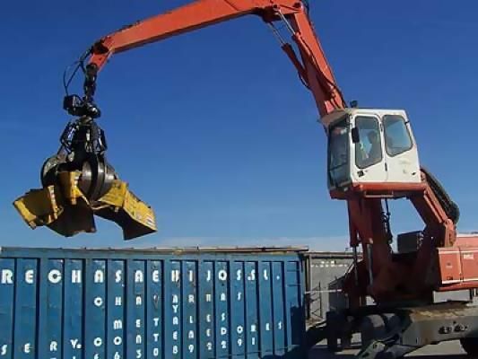 Una grúa está levantando algo sobre un contenedor azul que dice zona