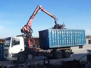 Una grúa está cargando un contenedor azul en un camión.