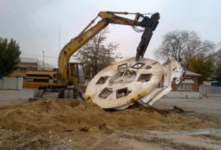 Una excavadora amarilla está levantando un objeto grande del suelo.