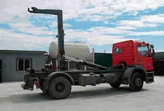 Un camión volquete rojo está estacionado frente a un edificio.