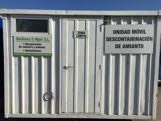 Un edificio blanco con un cartel que dice Unidad móvil de descontaminación de amianto.