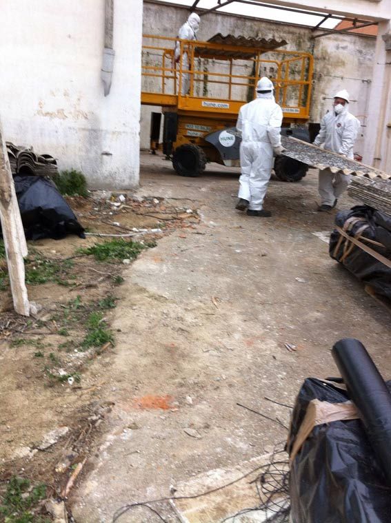 Un hombre con traje de protección lleva un trozo de amianto.