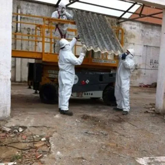 Un hombre con traje blanco sostiene un trozo de amianto.