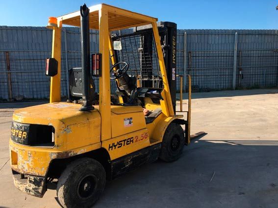 Una carretilla elevadora amarilla está estacionada frente a una valla.