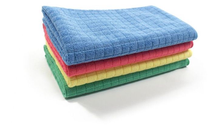 Neljän värikkään mikrokuituisen puhdistusliinan pino: sininen, punainen, keltainen ja vihreä.