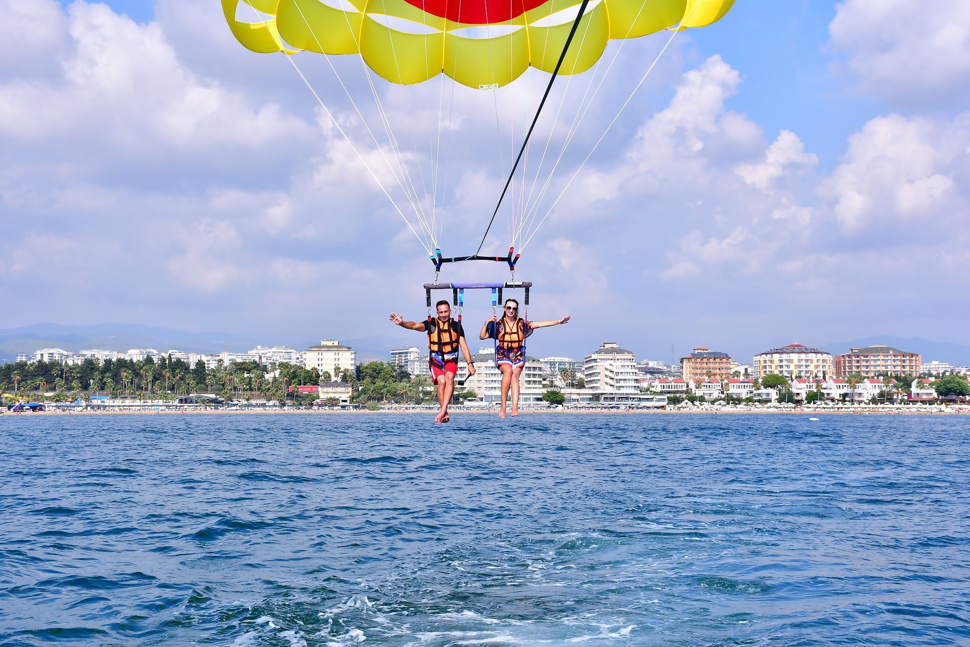 Deux personnes font du parachute ascensionnel au-dessus de l'eau bleue avec un parachute jaune.