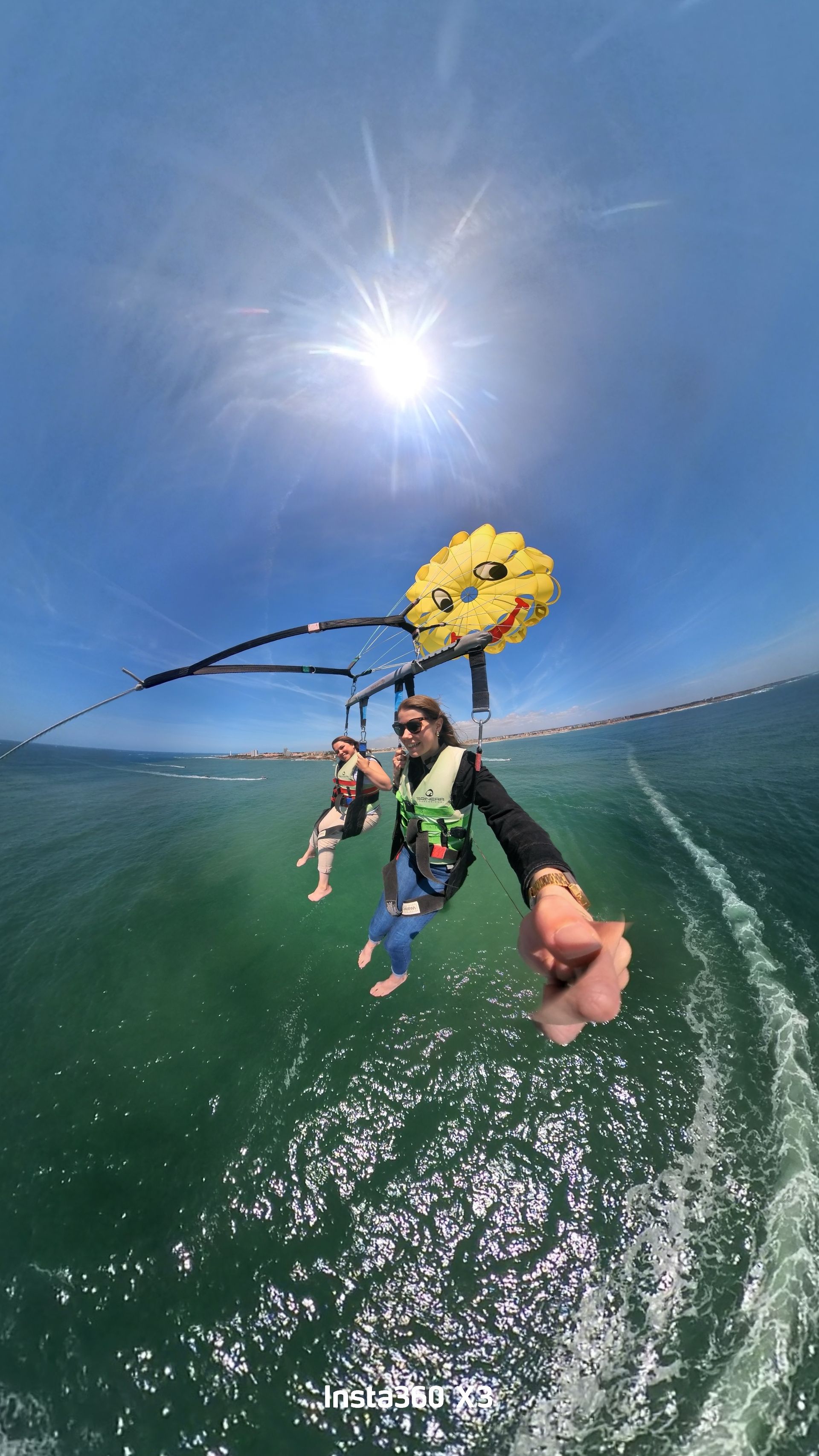 Parachute ascensionnel coloré au-dessus d'un petit bateau sur l'océan d'un bleu éclatant sous un ciel partiellement nuageux
