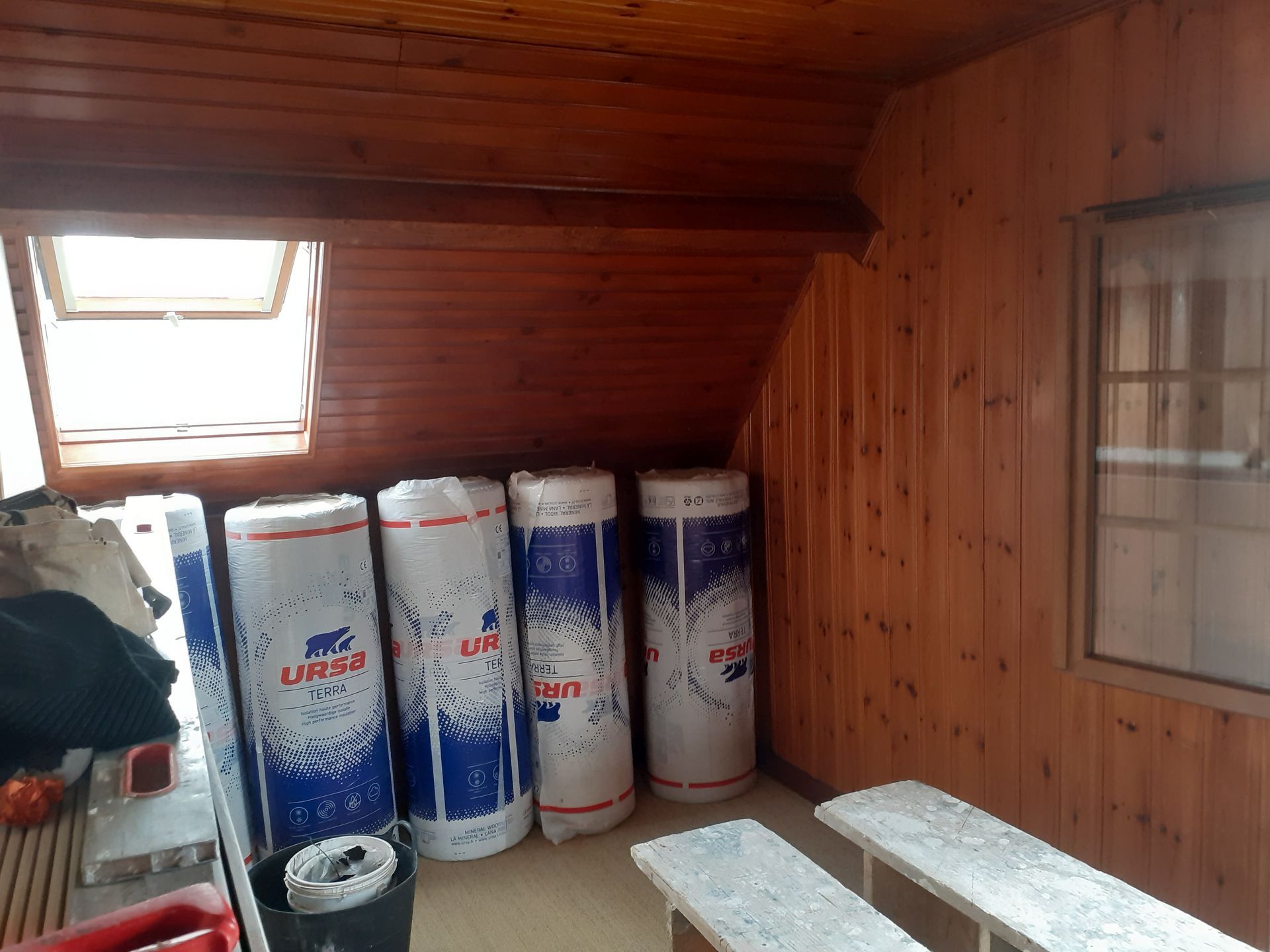 Rouleaux d'isolant neufs entreposés dans des combles