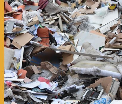 Tas de déchets mélangés comprenant du carton, du papier et des morceaux de meubles.