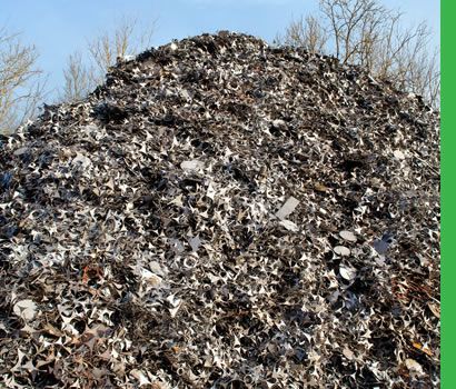 Tas de ferraille, probablement dans un centre de recyclage, sur fond de ciel bleu.