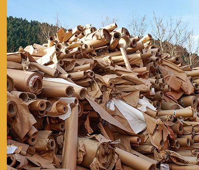 Pile de papier kraft roulé à l'extérieur, probablement destiné au recyclage.