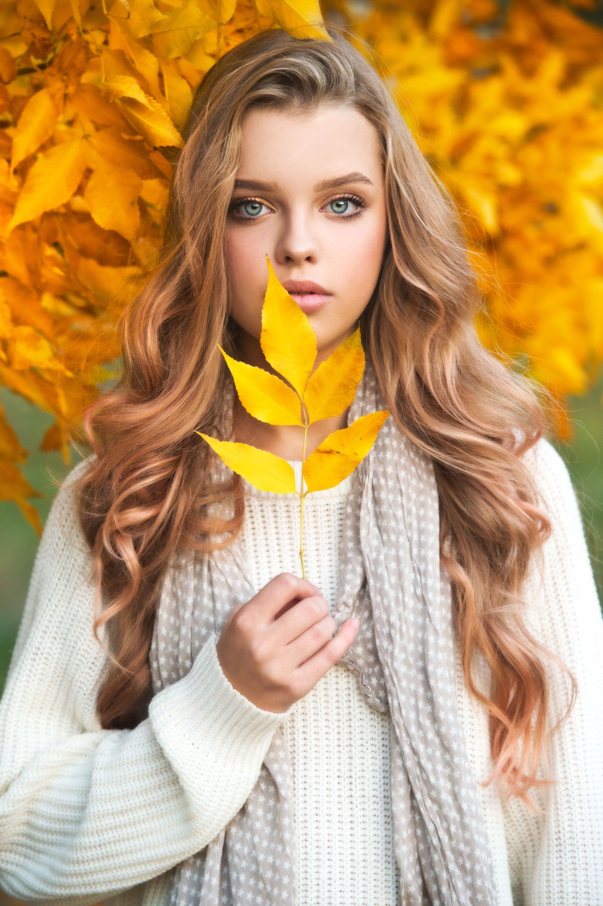 Jeune femme en train de tenir une feuille d'arbre jaune