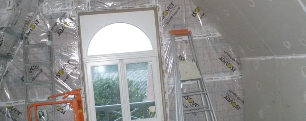 Pièce mansardée en rénovation avec murs isolés et une grande fenêtre laissant entrer la lumière du jour
