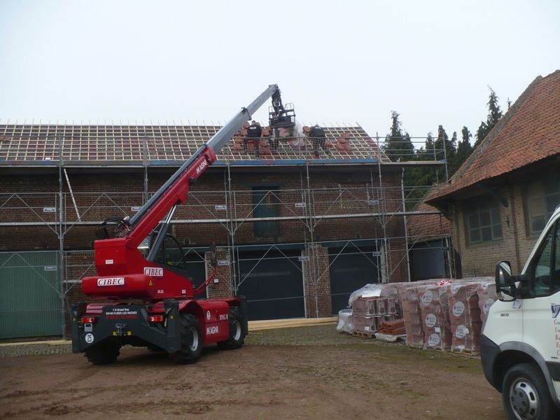 Nacelle télescopique rouge atteignant le toit d'un chantier recouvert d'échafaudages