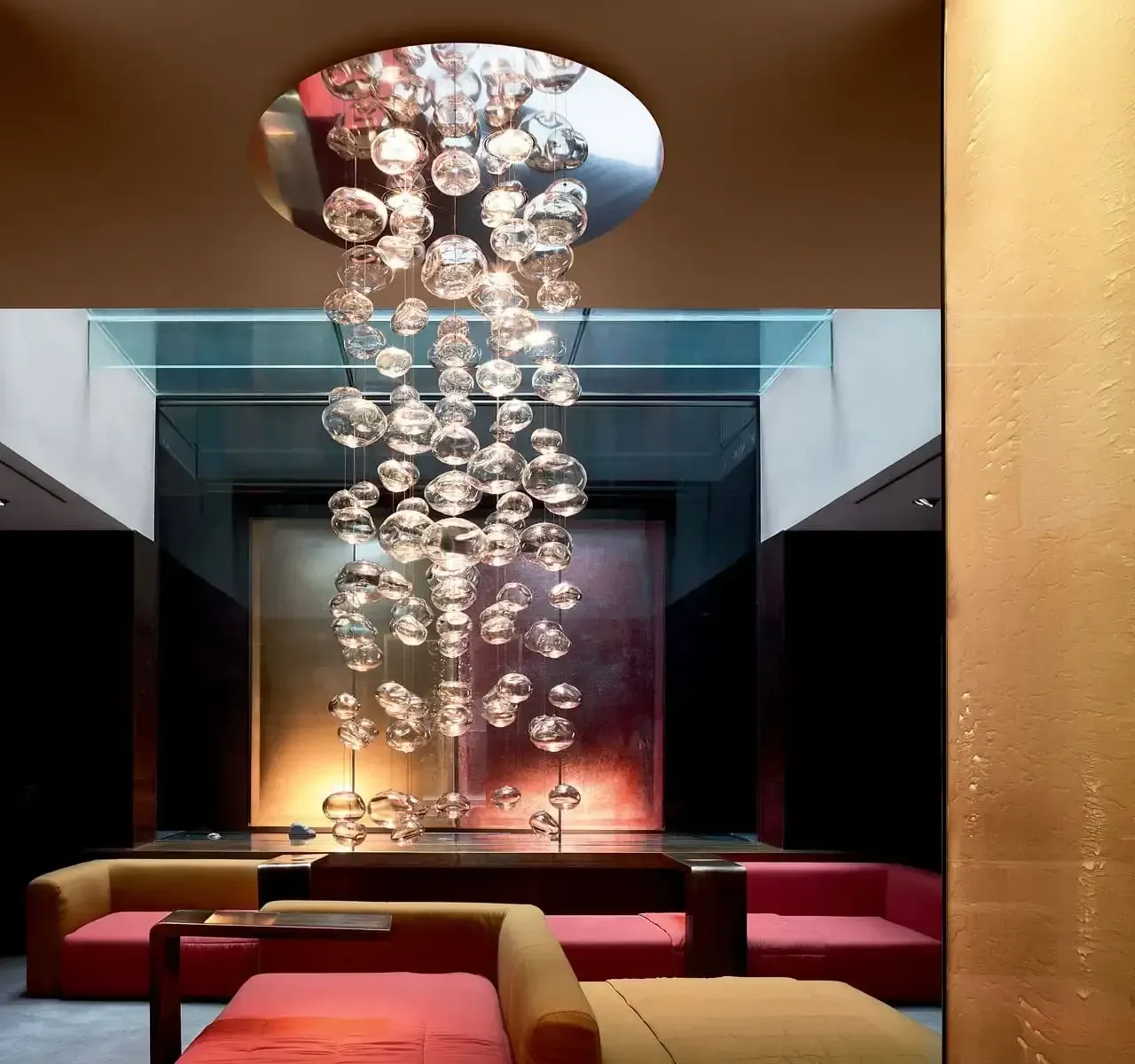 Una oficina de planta abierta con escritorios blancos, sillas negras, y un techo blanco con paneles de luces LED.