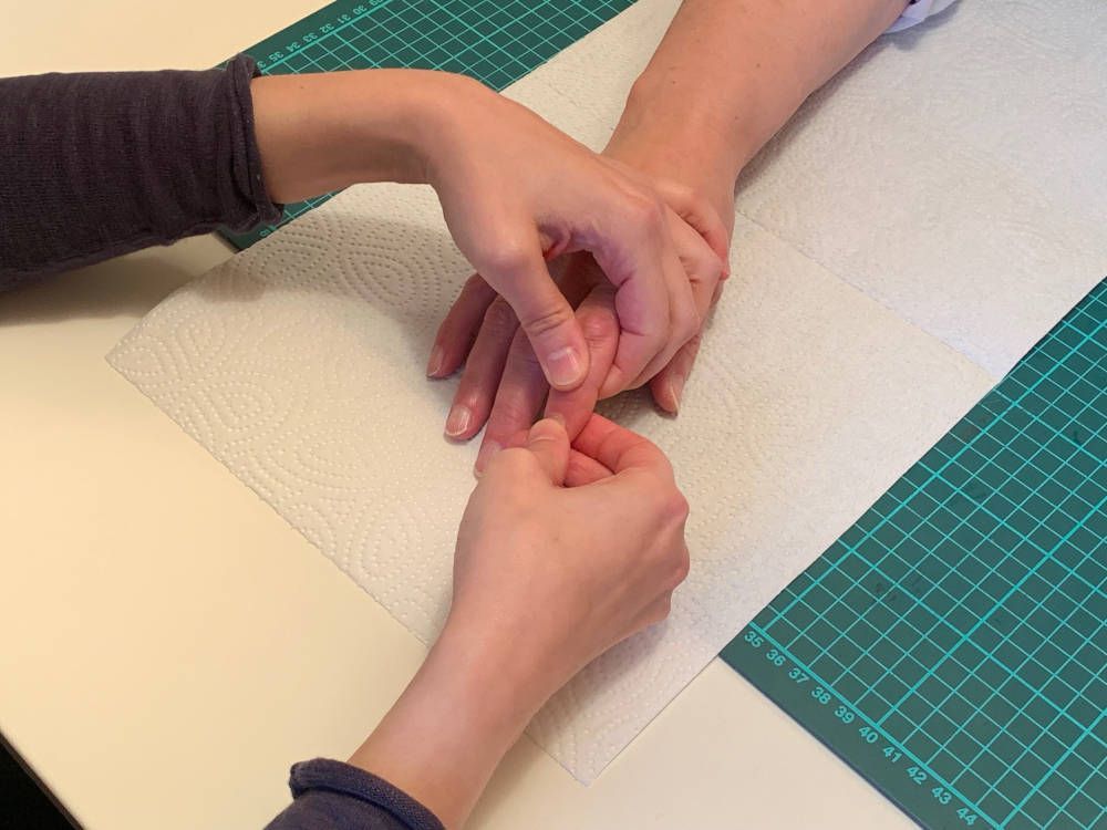 Eine Person trägt Nagellack auf die Nägel einer anderen Person auf.