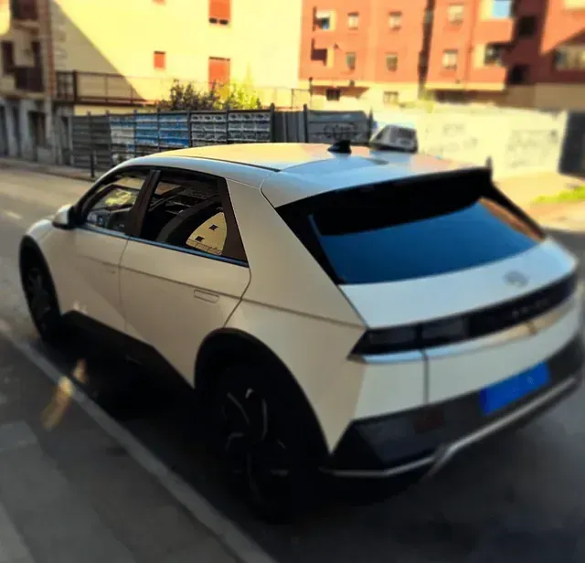 Un coche blanco está aparcado al costado de la carretera.