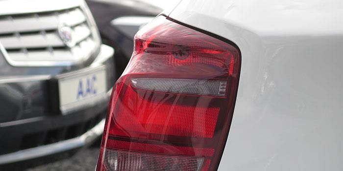 Ein weißes Auto mit rotem Rücklicht parkt neben einem schwarzen Auto.