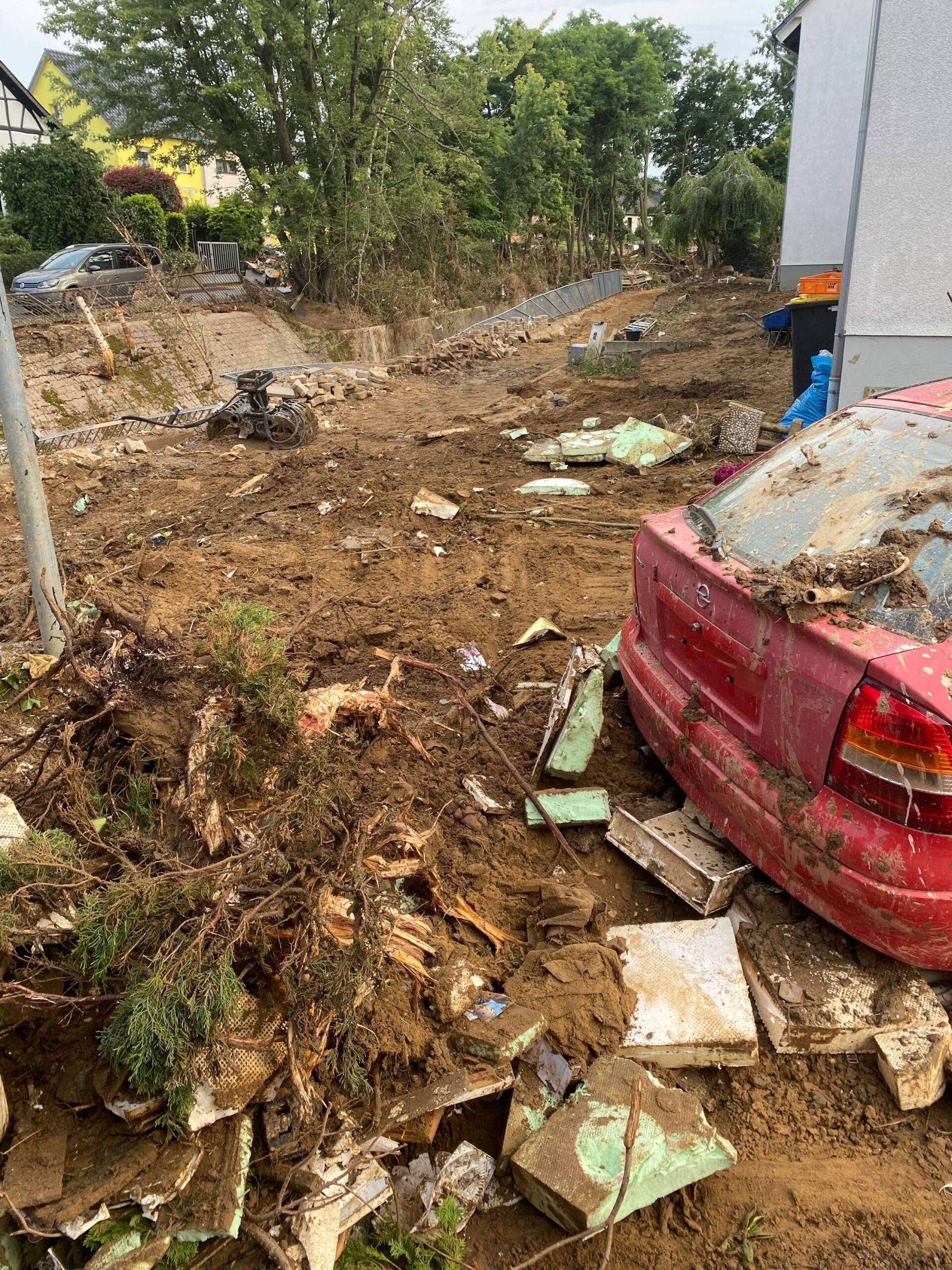 Auswirkungen der Flutkatastrofe mit einem kaputten Wagen und Schrott.