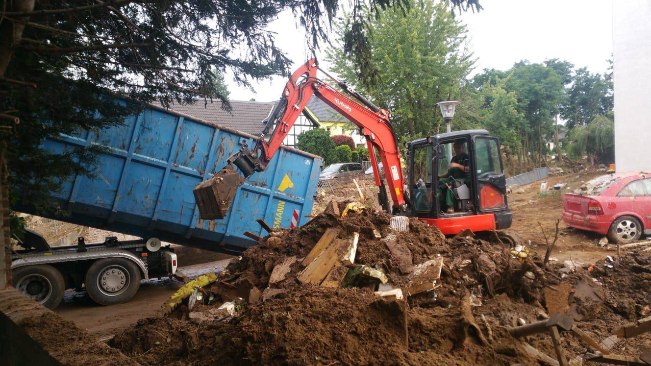 Ein Bagger verräumt Erdboden und Schrott in einen Container.
