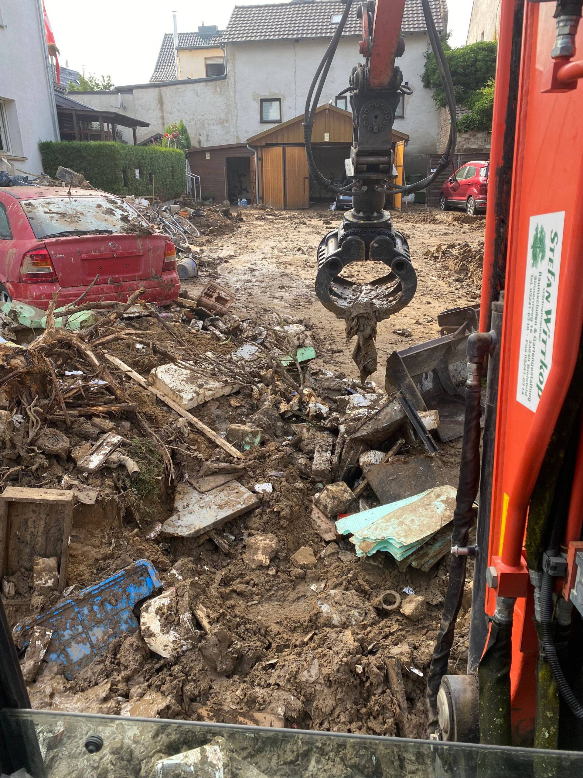 Ein Bagger mit Zange räumt den Müll von der Flutkatastrofe auf.