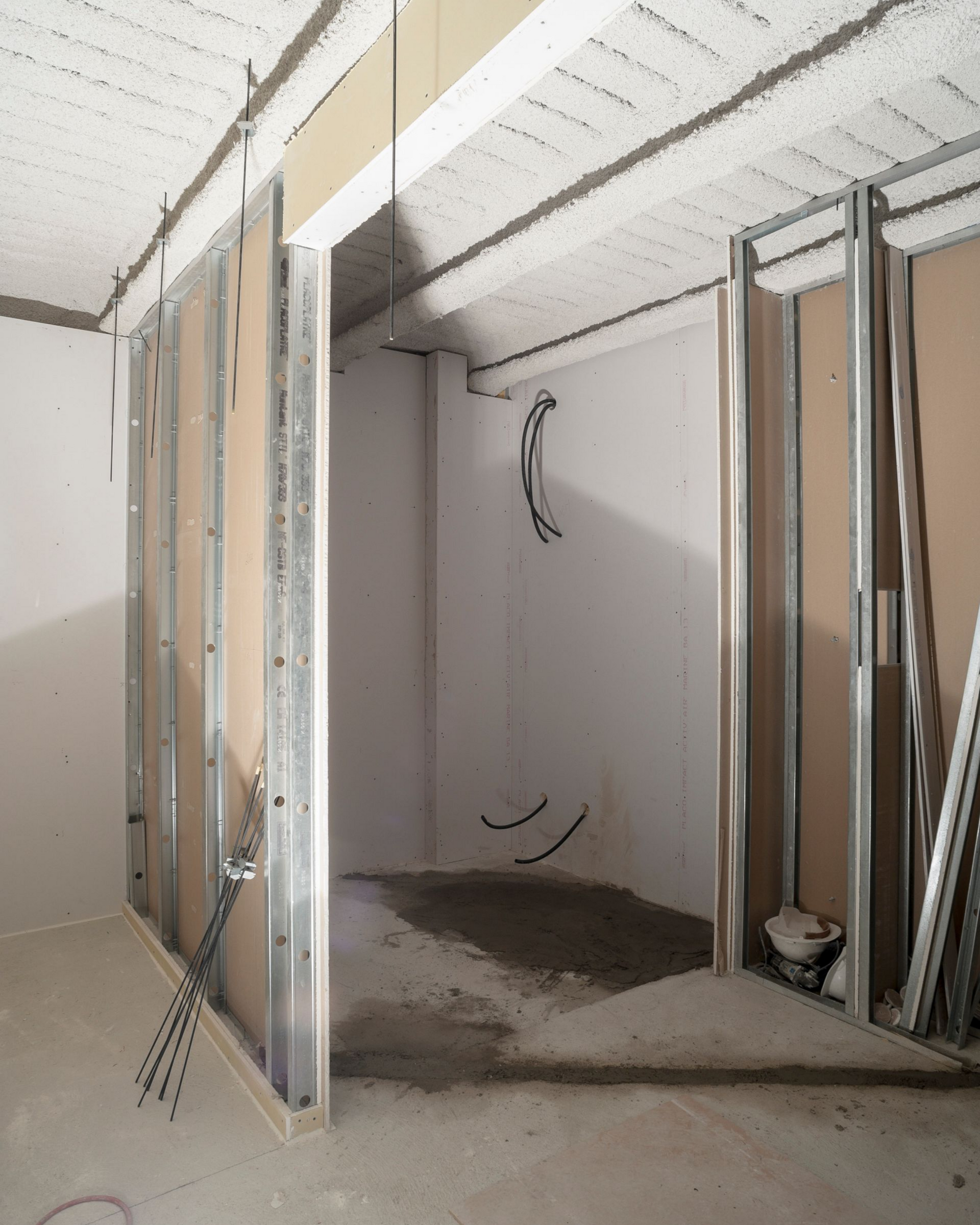 Intérieur d'une pièce en construction, avec une structure métallique et des câbles apparents.