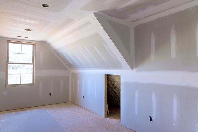 Pièce intérieure avec murs et plafond en plaques de plâtre non finies ; comprend une fenêtre et une porte.