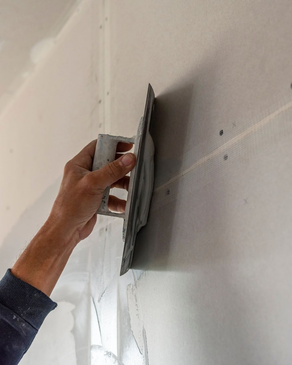 Une personne utilise une truelle pour appliquer du plâtre sur un mur.