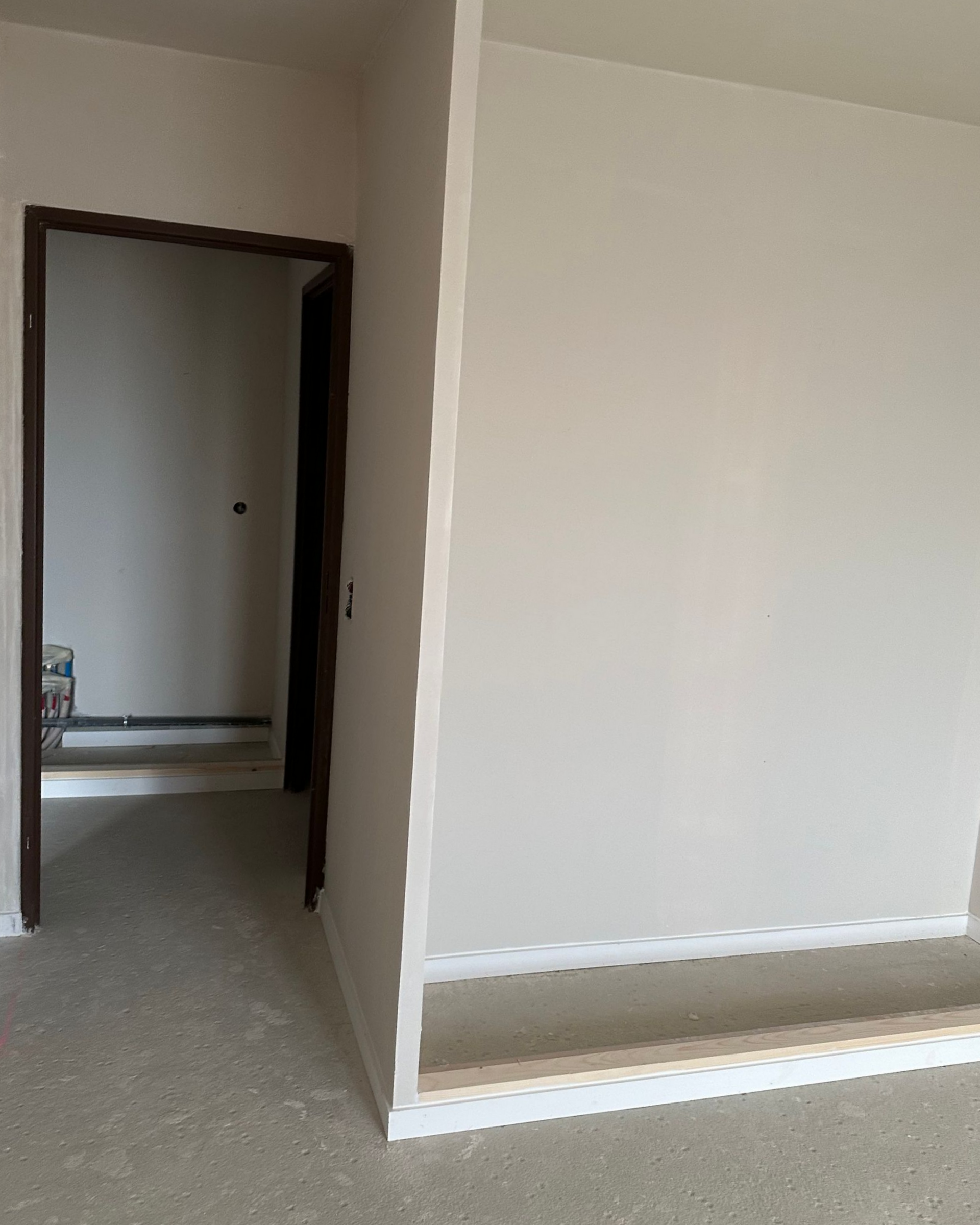 Pièce intérieure en construction avec porte, murs et sol.