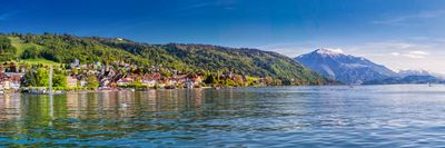 Ein See mit Bergen im Hintergrund und einer kleinen Stadt im Vordergrund. Seerestaurant zum Schlüssel da Andrea