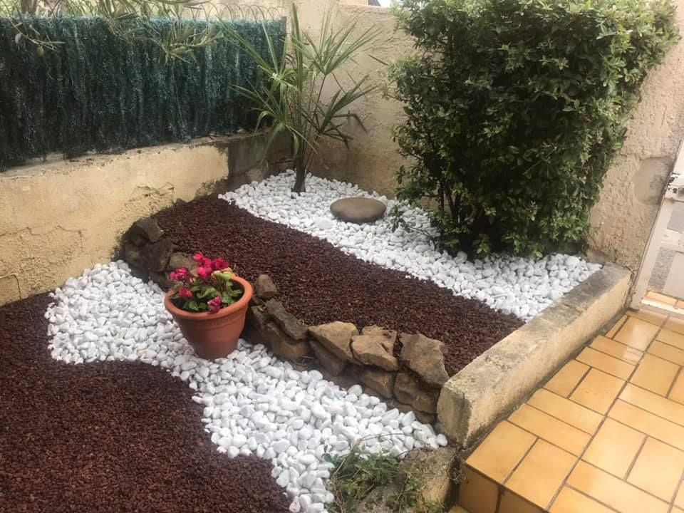 Pose de graviers rouge et blanc avec des plantations et pots de fleurs