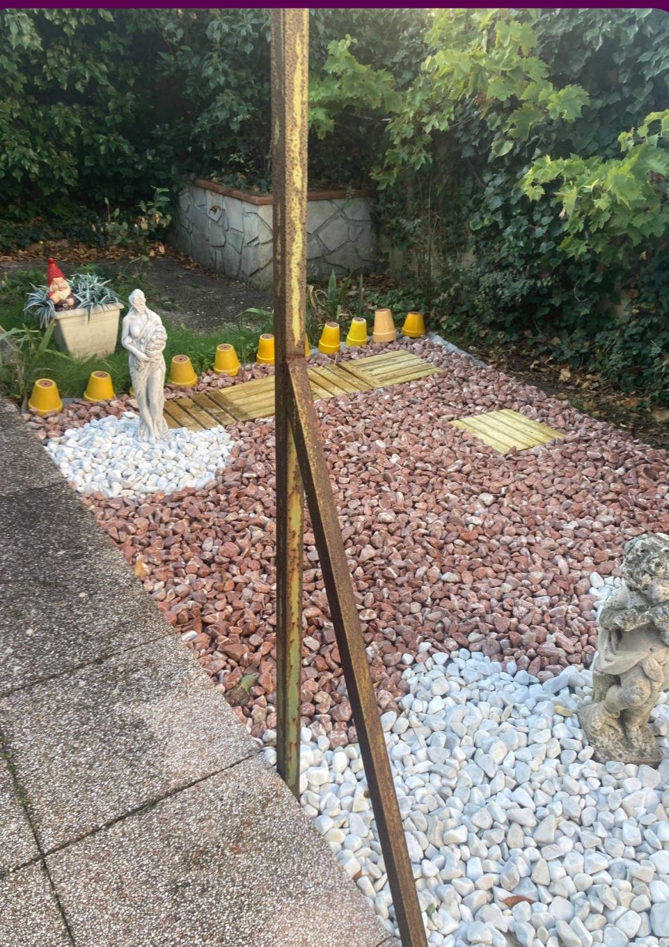 Pose de graviers rouge et blanc avec des statues et des pots jaunes