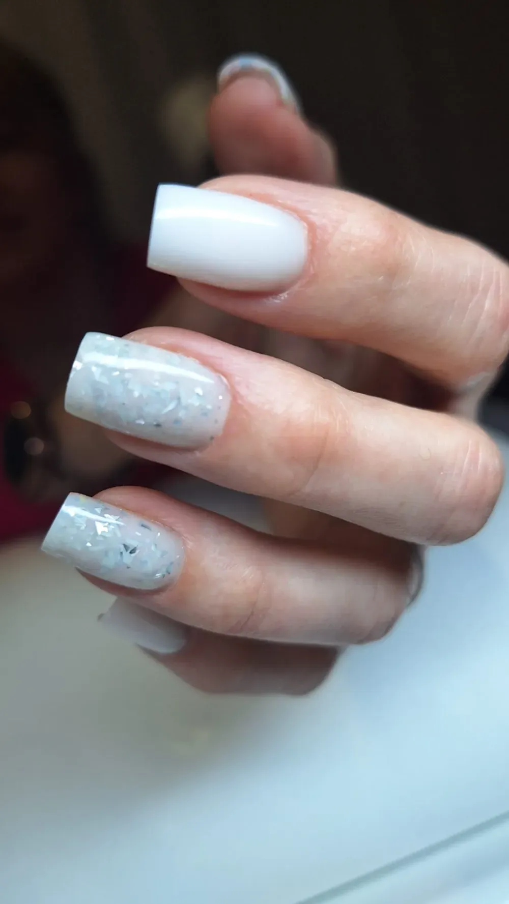 Primer plano de mano con uñas acrílicas cuadradas blancas y brillantes.