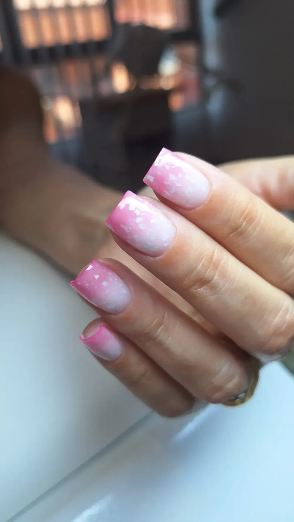 Arte de uñas ombré en rosa y blanco en una mano con uñas de forma cuadrada.