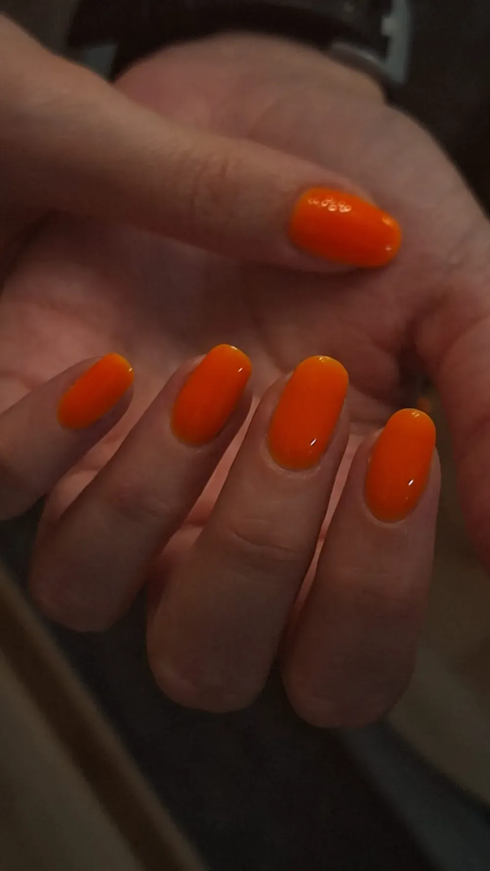 Mano con esmalte de uñas naranja.