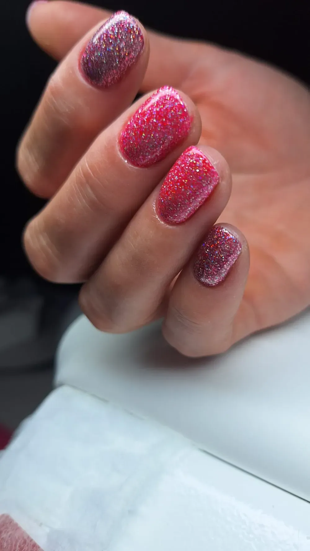 Mano con esmalte de uñas rosa brillante.