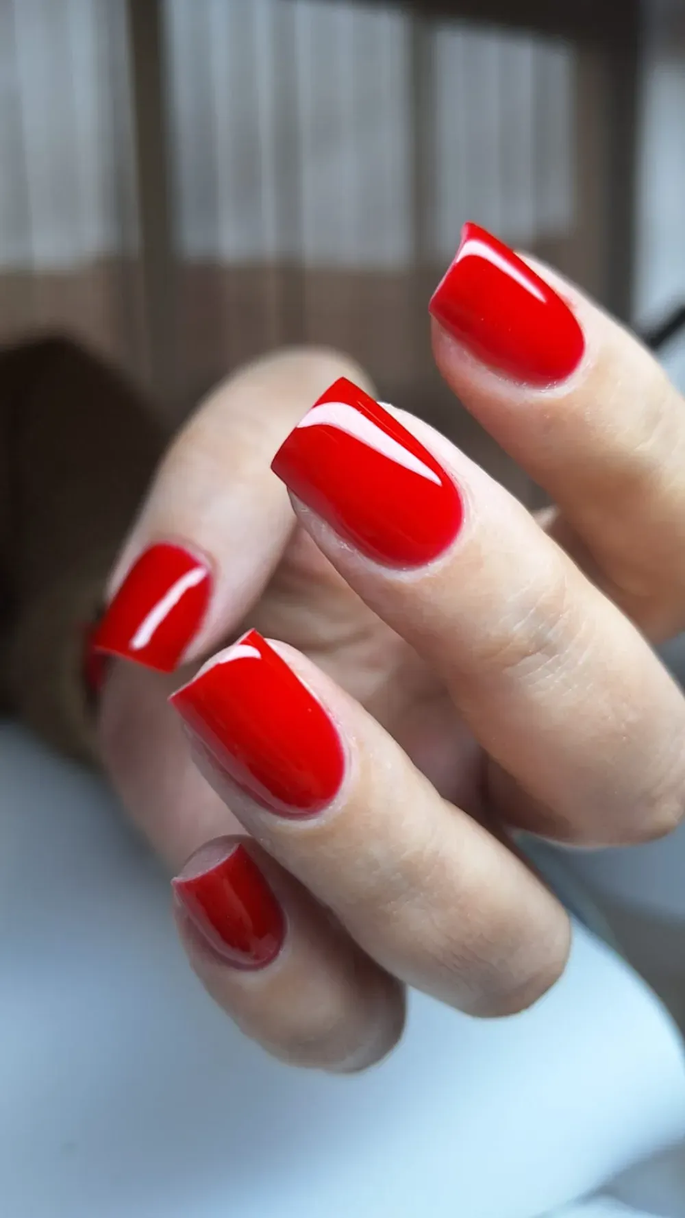 Mano con uñas pulidas, cuadradas y de color rojo brillante.