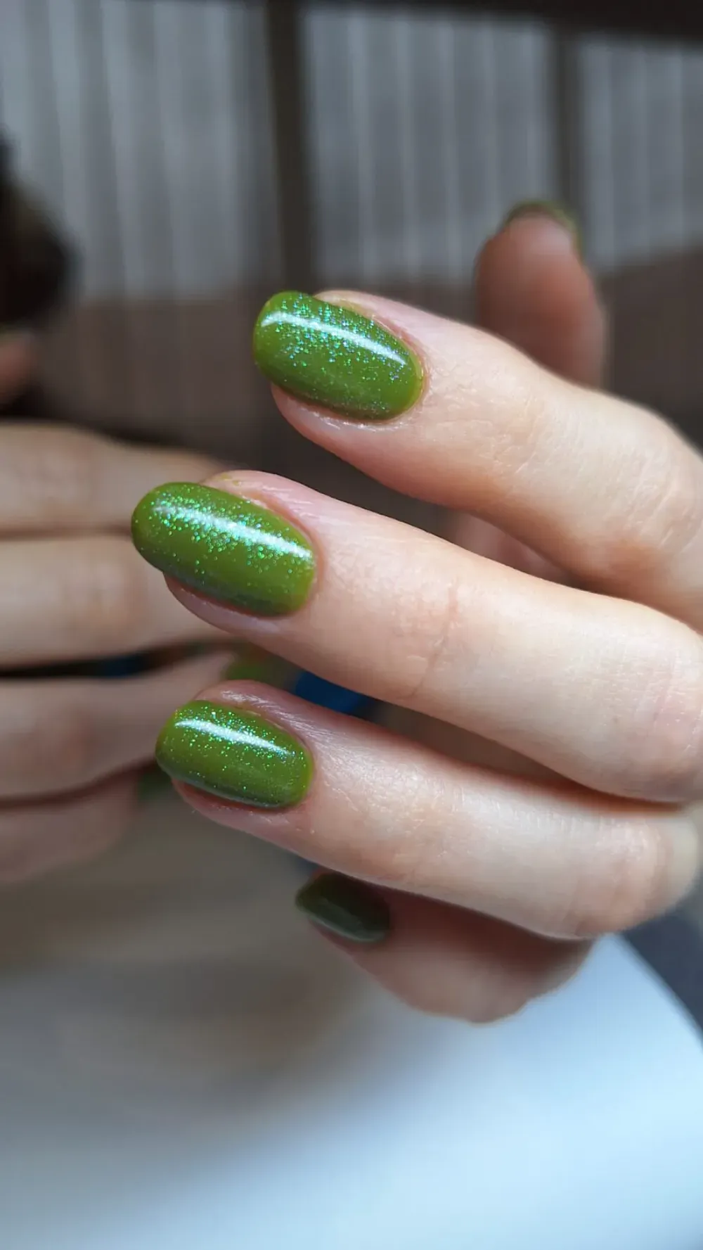 Primer plano de una mano con uñas de forma ovalada pintadas de un color verde brillante.