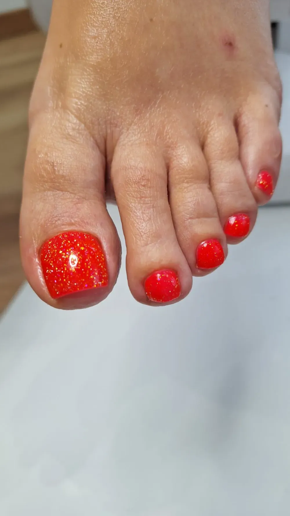 Pie con esmalte de uñas con brillantina roja.