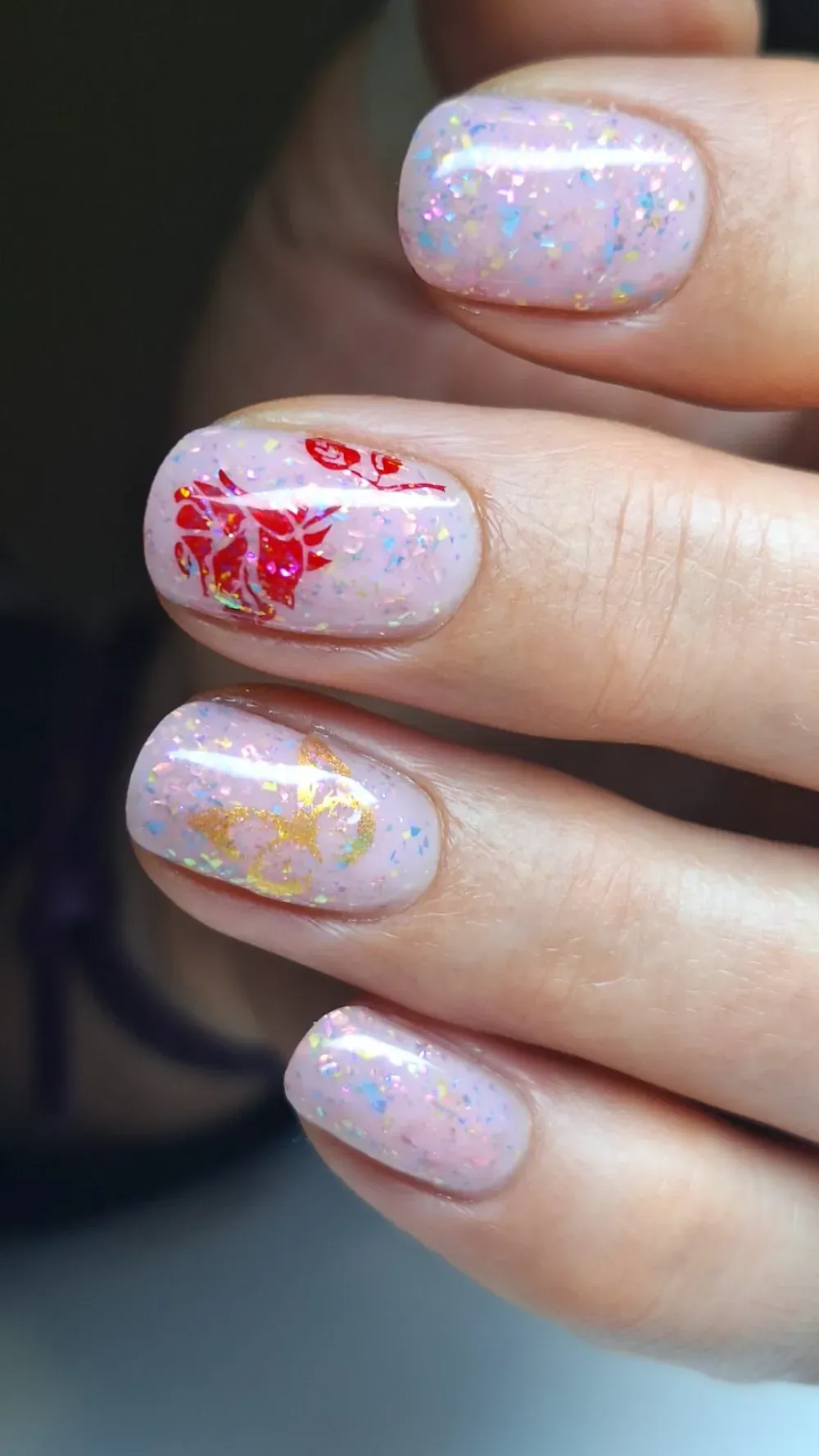 Uñas rosa claro con brillo y diseños florales.