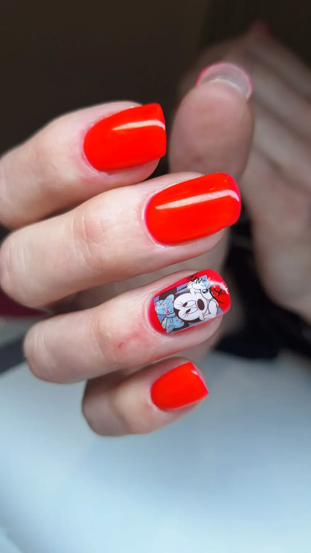 Manicura de uñas rojas con diseño de calavera en una de las uña.