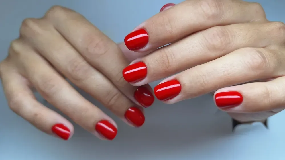 Manos con esmalte de uñas rojo, expuestas sobre un fondo claro.