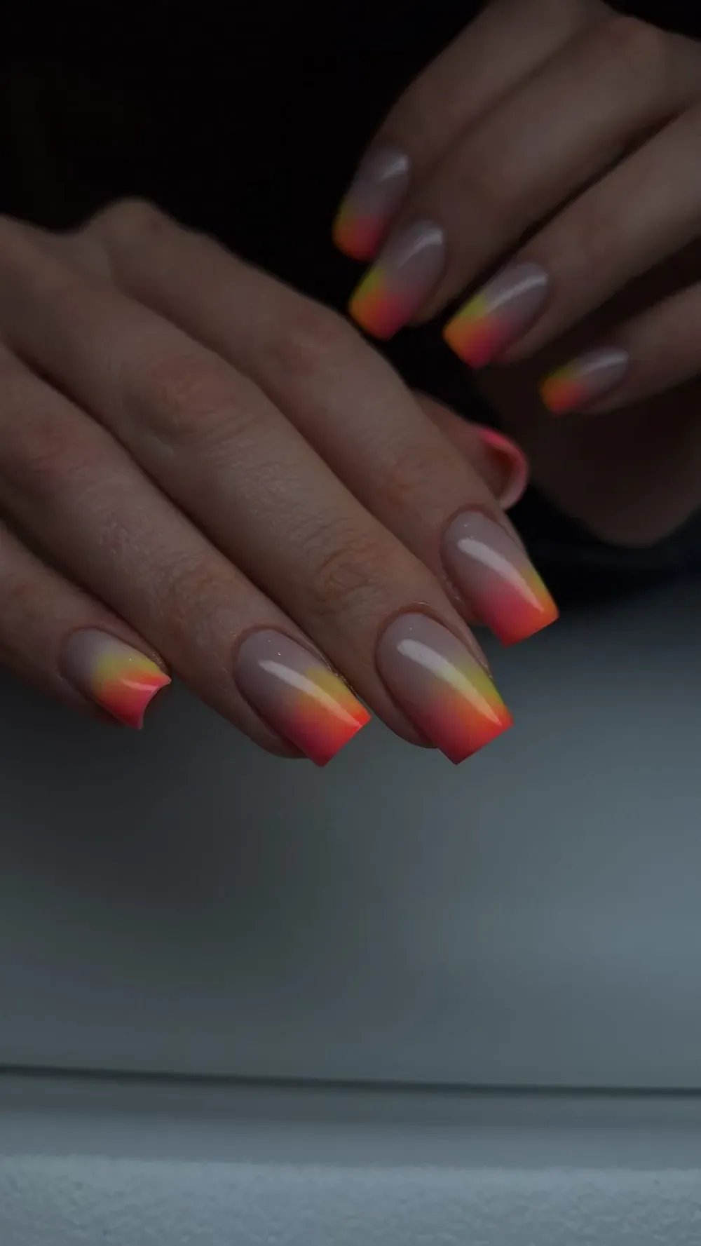 Manos con uñas en forma de ataúd que presentan un degradado de naranja y amarillo sobre una base nude.