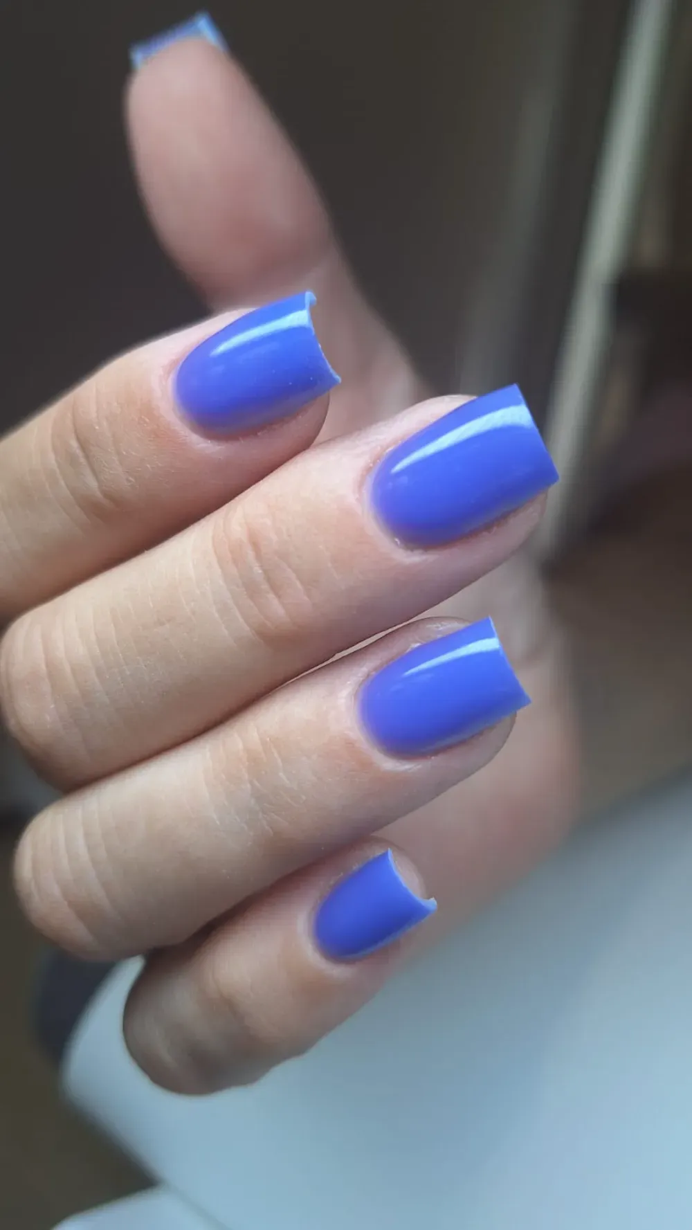 Mano con uñas pintadas de un color azul sólido y brillante.