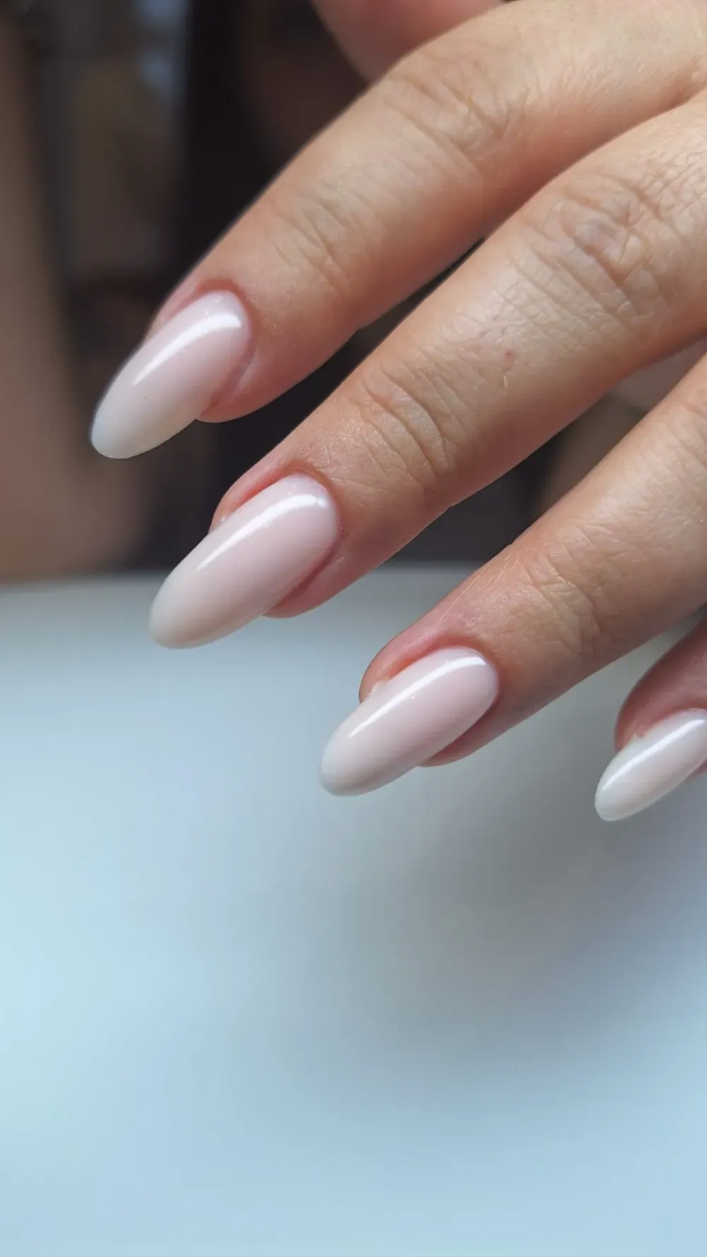 Mano con uñas de forma ovalada pintadas en tono rosa pálido.