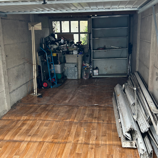 Intérieur de garage avec rangement encombré et plancher de bois.