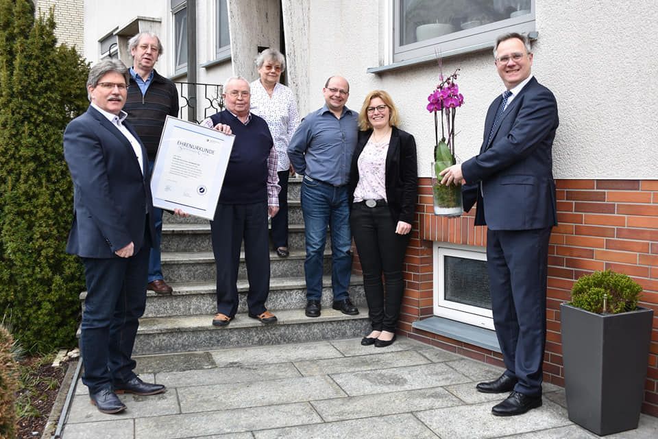 Eine Gruppe von Menschen steht vor einem Gebäude und schüttelt sich die Hände.