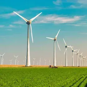 Una hilera de turbinas eólicas situadas encima de un exuberante campo verde.