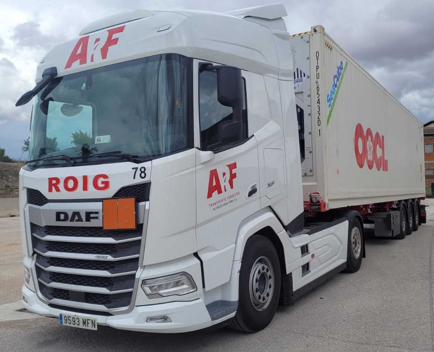 Camión semirremolque A&F blanco transportando un contenedor con la marca OOCL. Estacionado al aire libre; día soleado.